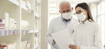 Two pharmacists looking at a paper together while standing inside the pharmacy