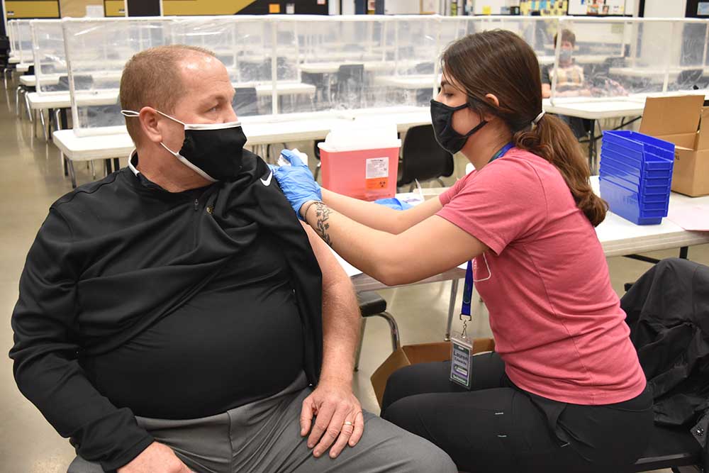 Craig Gibbs, principal of Fredericktown High School in Missouri, receiving his COVID-19 vaccine from Lauryn Edwards, a Parkland Health Mart Pharmacy team member on March 18, 2021.