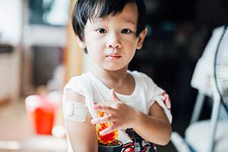 Child displaying band aid after receiving his vaccination