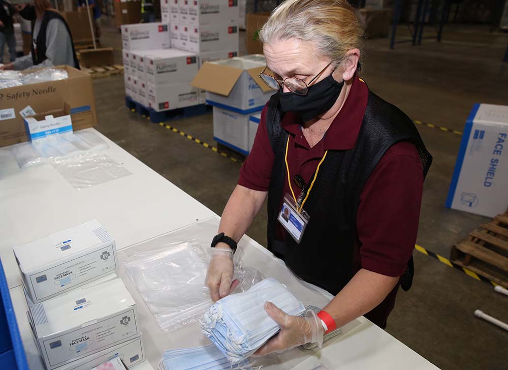 A worker assembles the contents of a COVID-19 vaccine ancillary supply kit at McKesson’s Manteno, IL distribution center.