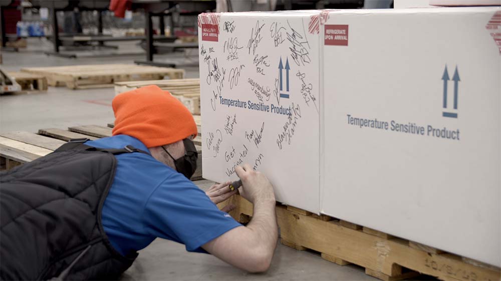 Workers at McKesson's Louisville, Ky. distribution center sign the first box of Janssen’s COVID-19 vaccines from Johnson & Johnson.