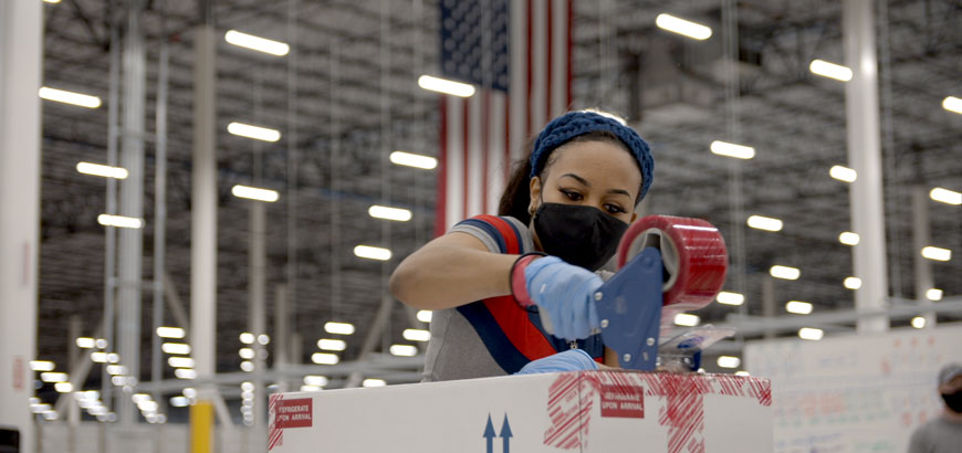 A worker in McKesson’s Louisville, Ky. distribution center prepares a box of COVID-19 vaccine doses for shipment