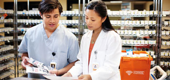 Highlighting Resiliency Two pharmacists look at paperwork behind the counter
