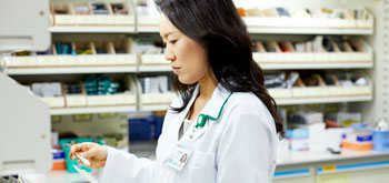 A pharmacist looks over paperwork behind the pharmacy counter