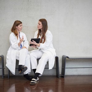 Mental-Support Two physicians sit together and talk in a hospital hallway<br>