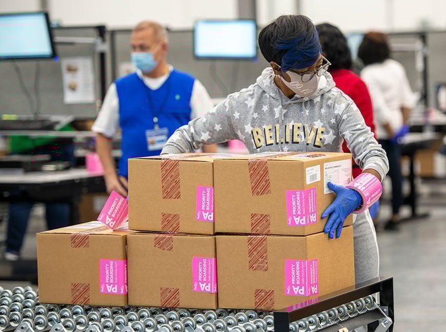 Employee packing boxes of Moderna vaccine for shipment Employee moving boxes of vaccines through a warehouse