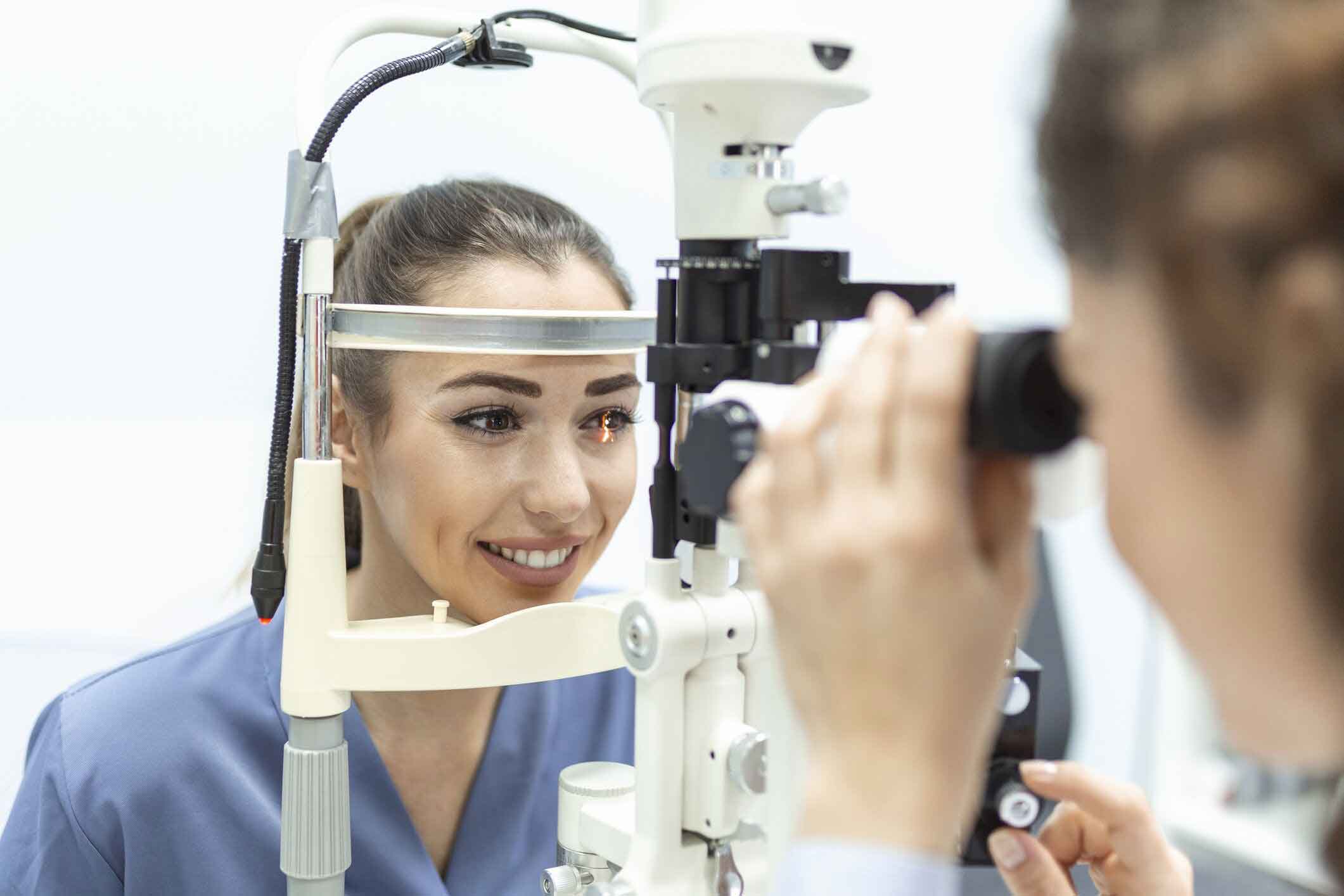 An eye doctor examines a patient's eyes using a slit lamp biomicroscope.