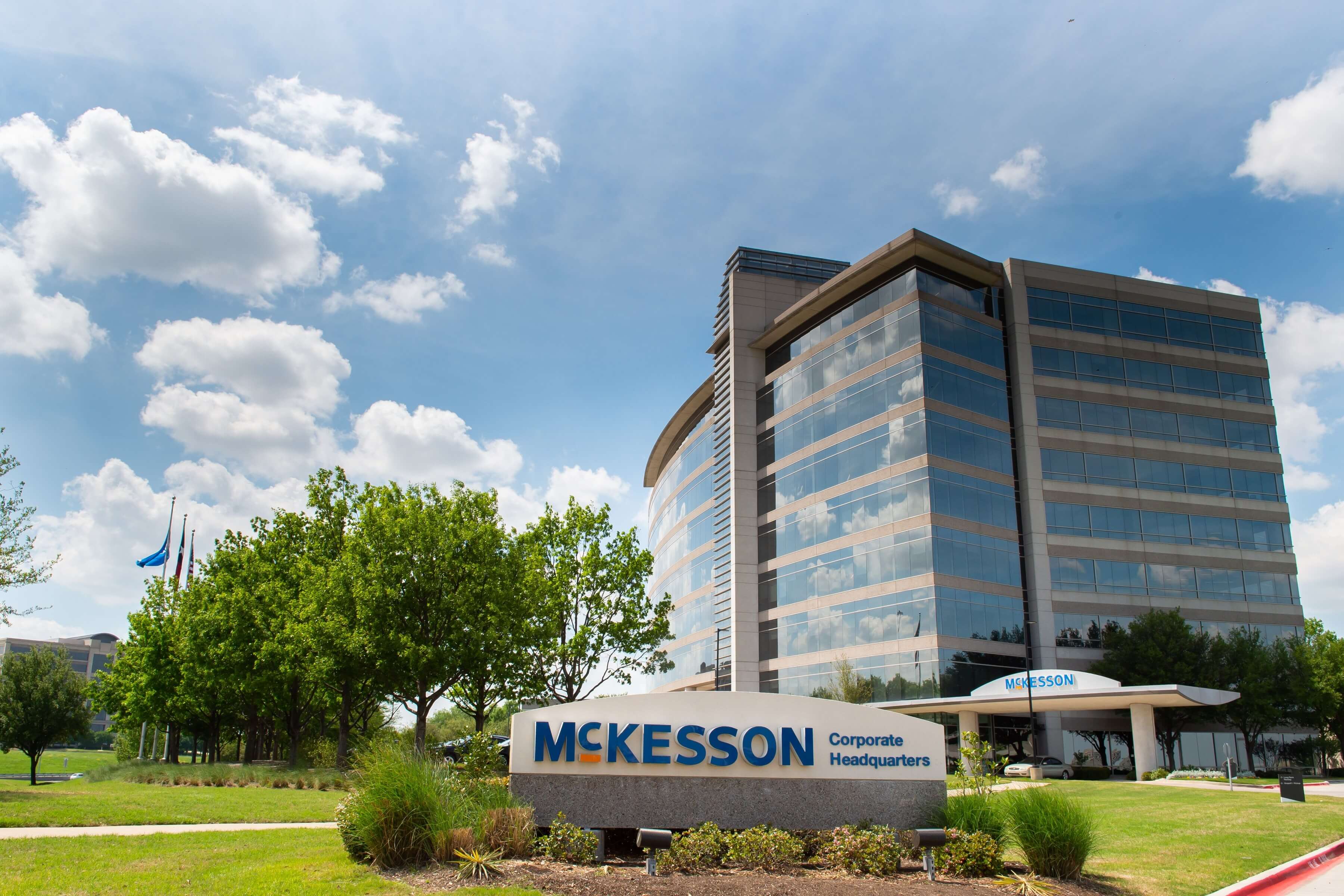 McKesson Corporate Headquarters in Irving, Texas with a modern glass building and a sign in the foreground on a sunny day.