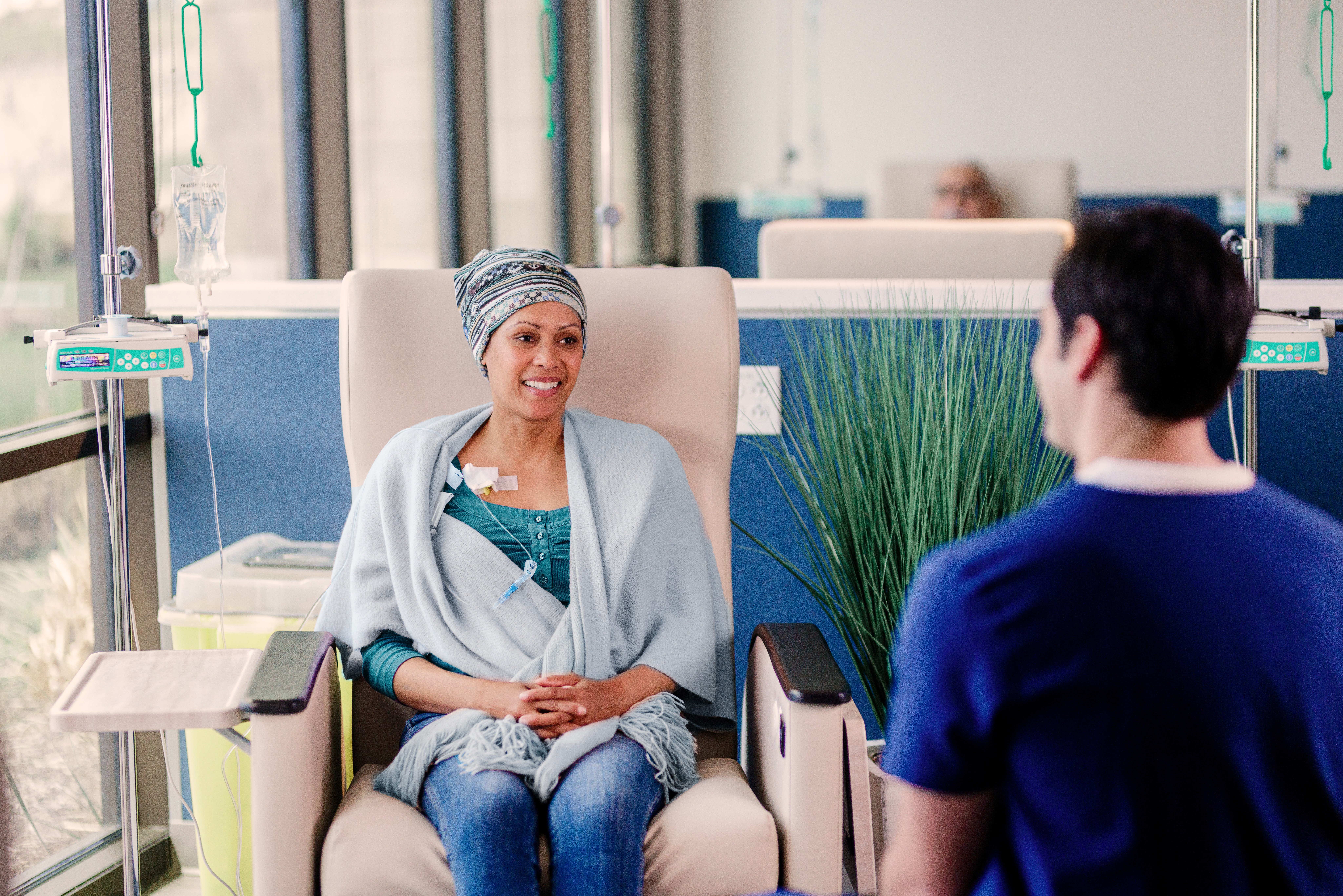 A person seated in a clinic chair receiving medical treatment with an IV drip attached.