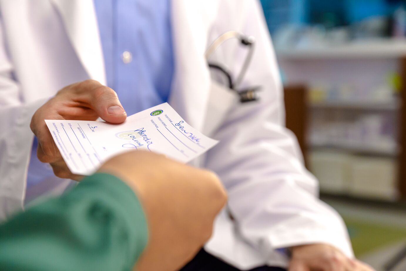 A doctor hands a prescription to a patient in an office setting.