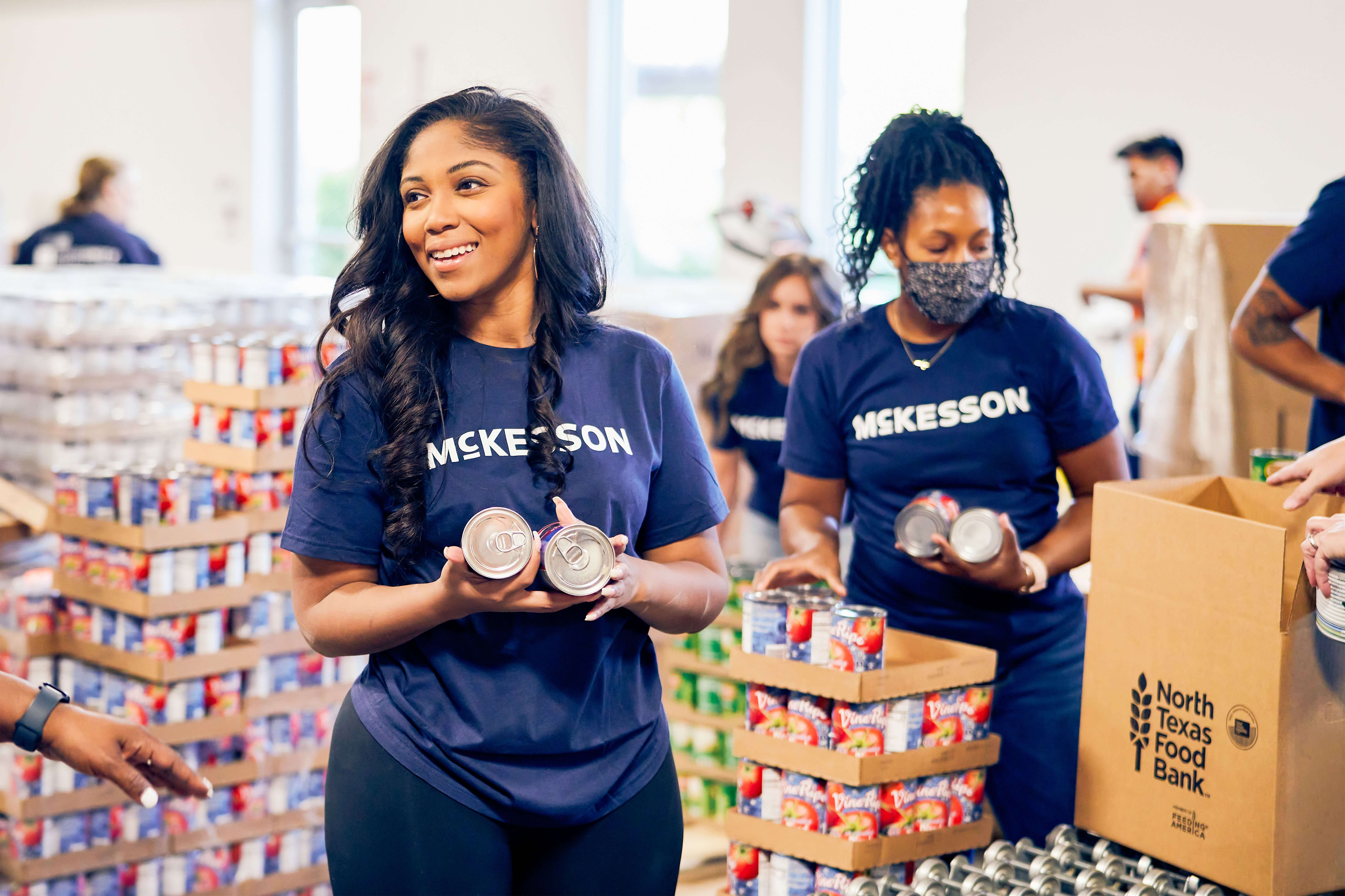Volunteers in McKesson shirts holding canned goods at North Texas Food Bank.