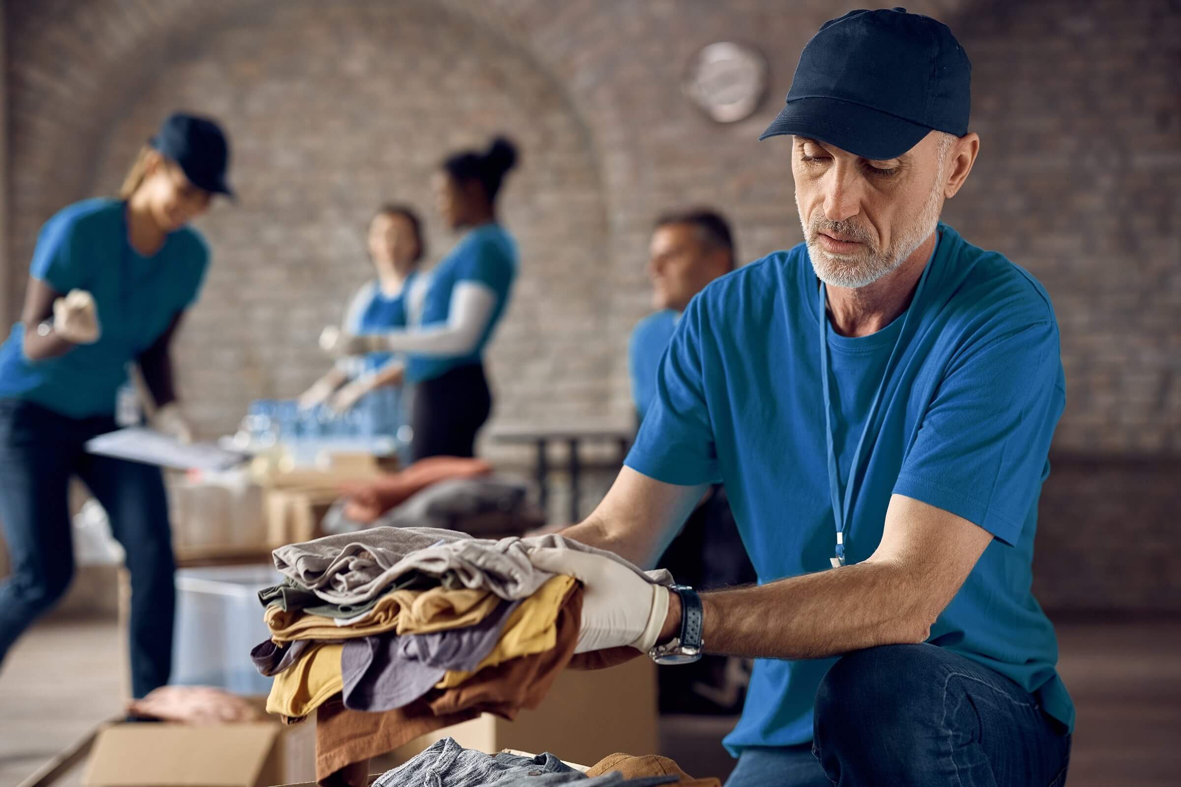 Volunteers sorting and folding clothes in a donation center.