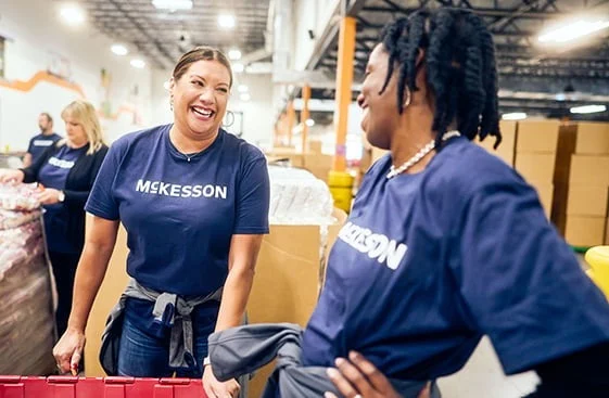 Two people in McKesson shirts working in a warehouse, one holding a red container.