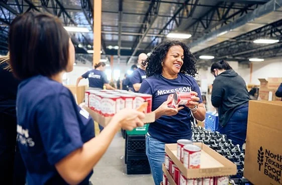 Volunteers in a warehouse packing canned goods into boxes.