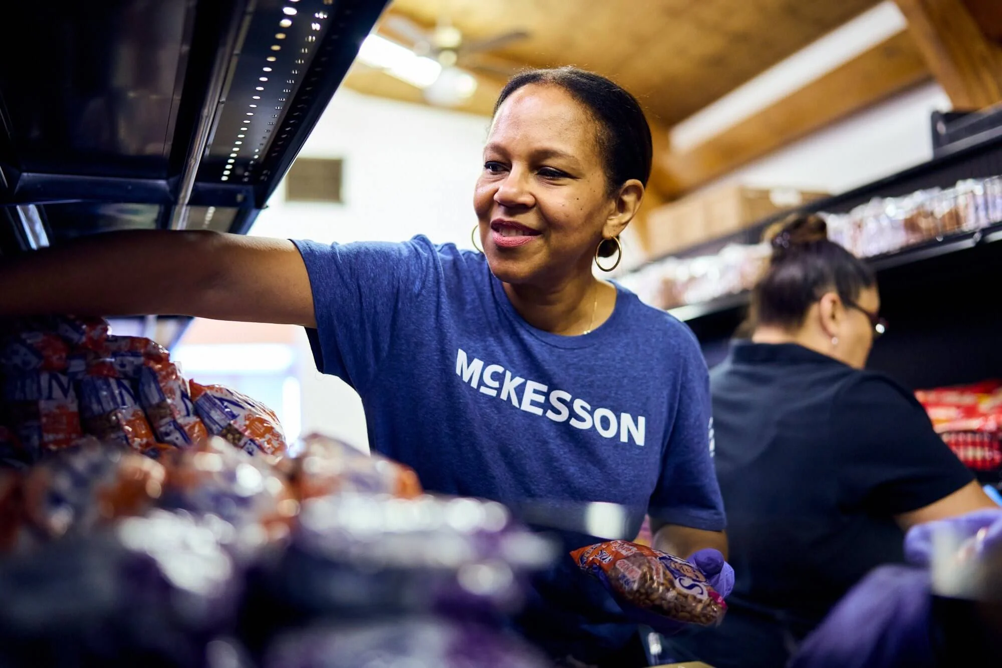 Person in a blue McKesson shirt stocking shelves in a store.