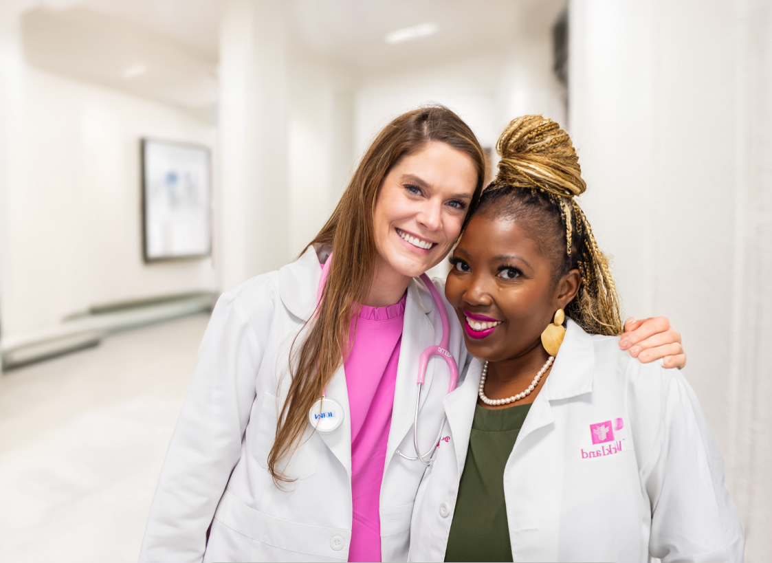 Two healthcare professionals in white coats standing together in a hospital hallway.