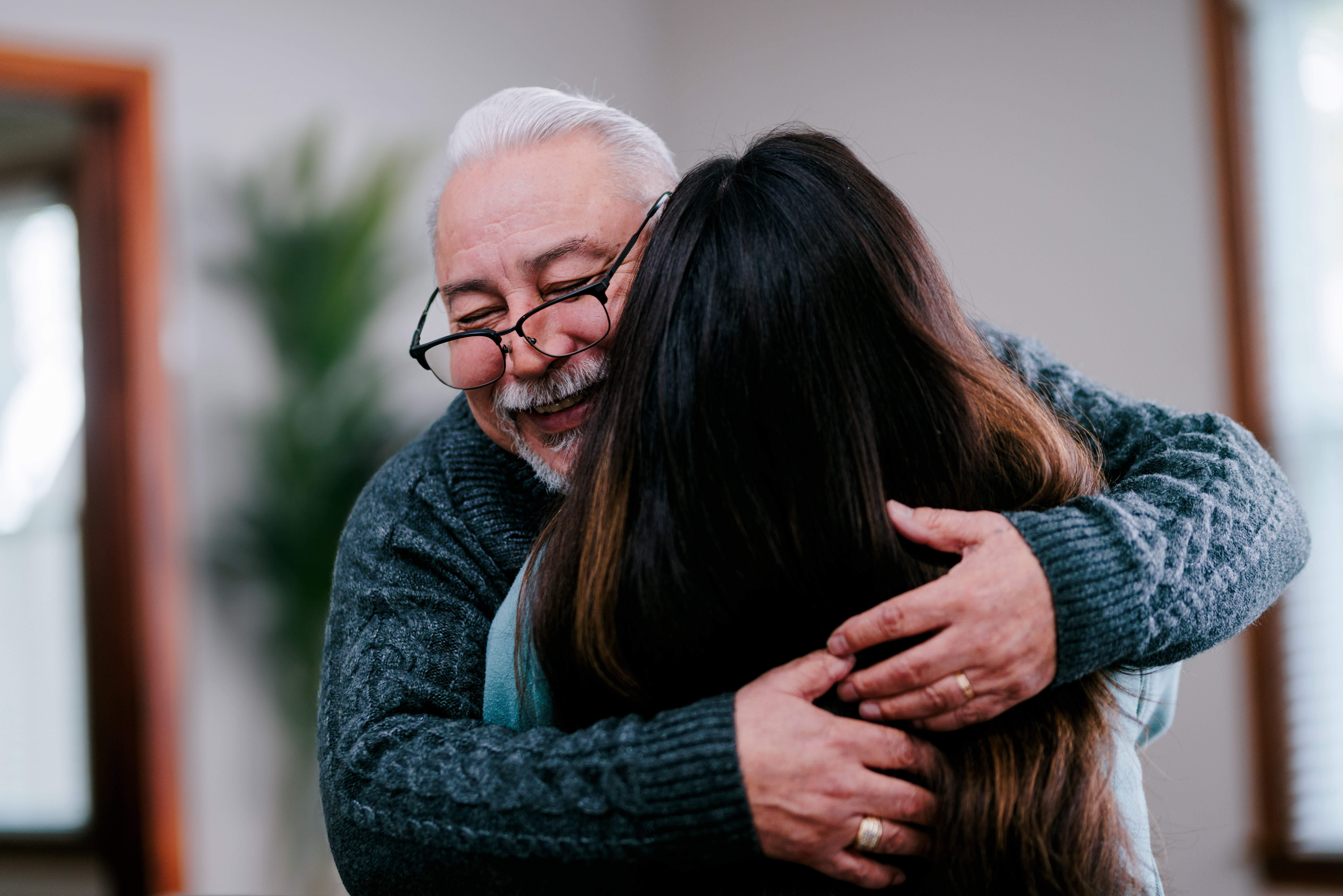Two people embracing each other in a hug indoors, with blurred faces for privacy.