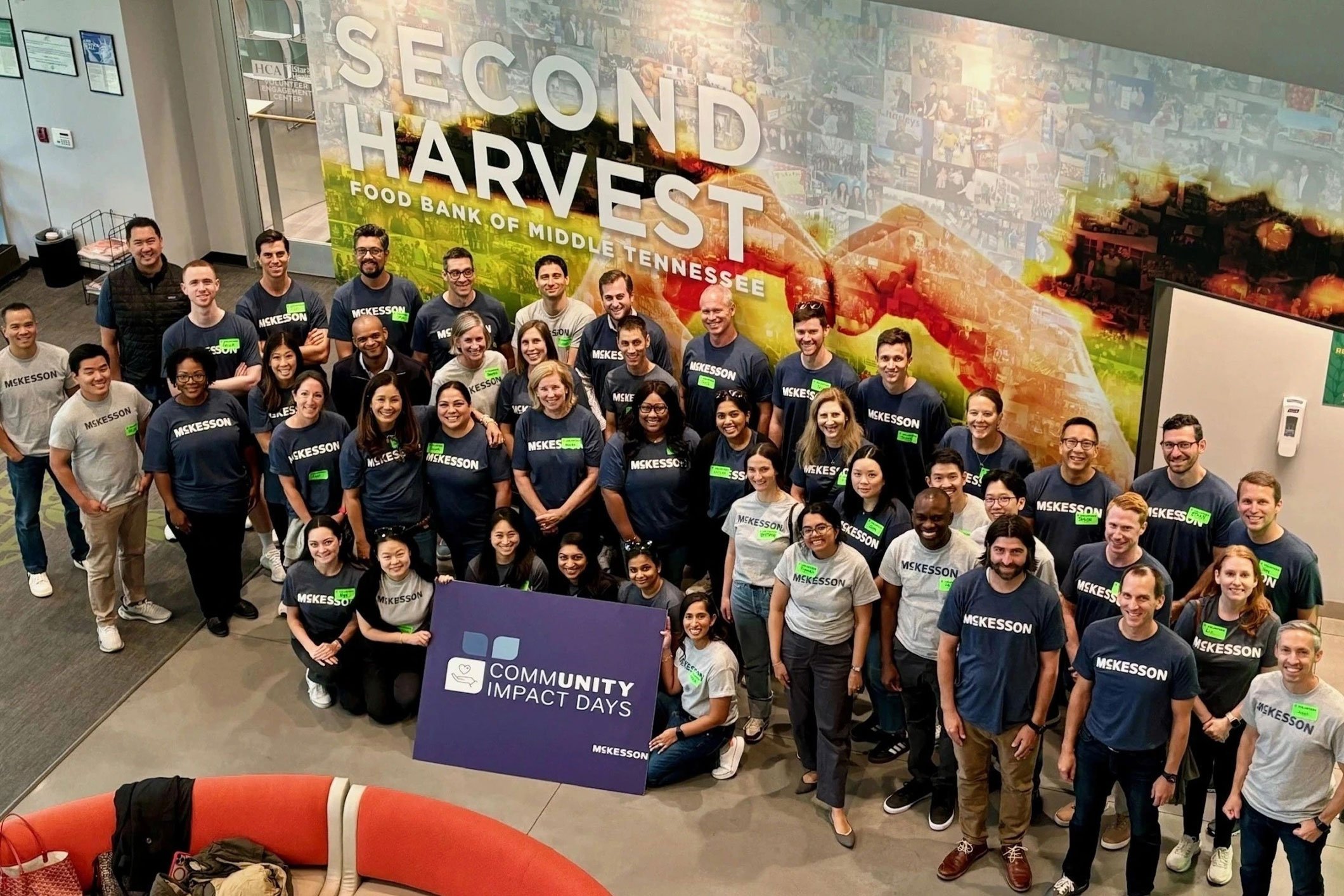 Group of people in "McKesson" shirts pose in front of a "Second Harvest Food Bank of Middle Tennessee" wall holding a "Community Impact Days" sign.