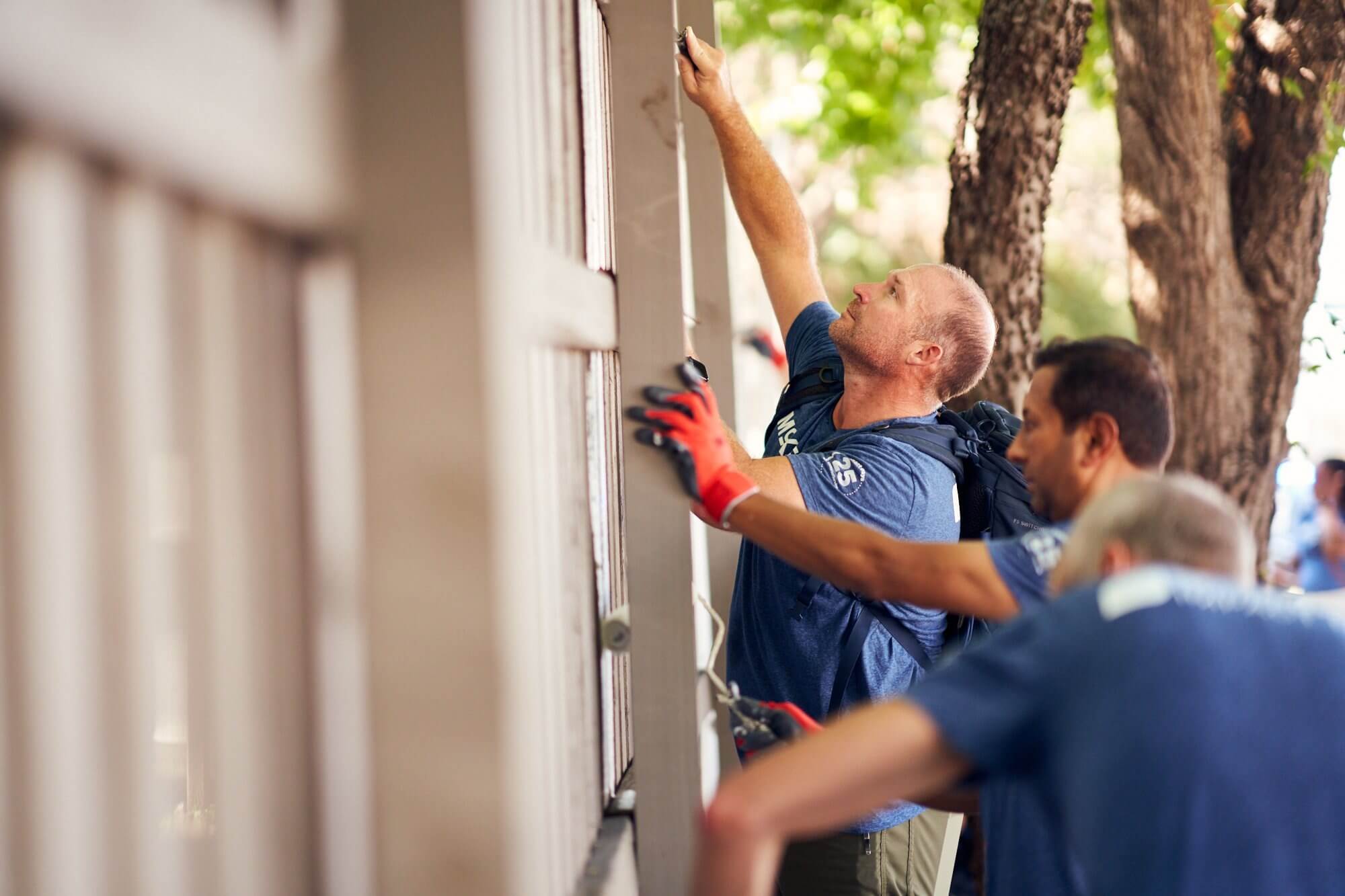 People painting a building exterior with brushes and rollers.