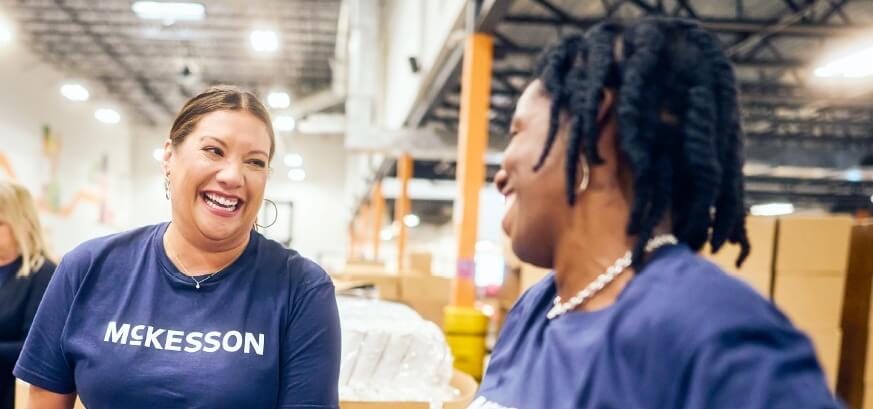 Two people wearing blue McKesson shirts are talking in a warehouse with boxes and shelves in the background.