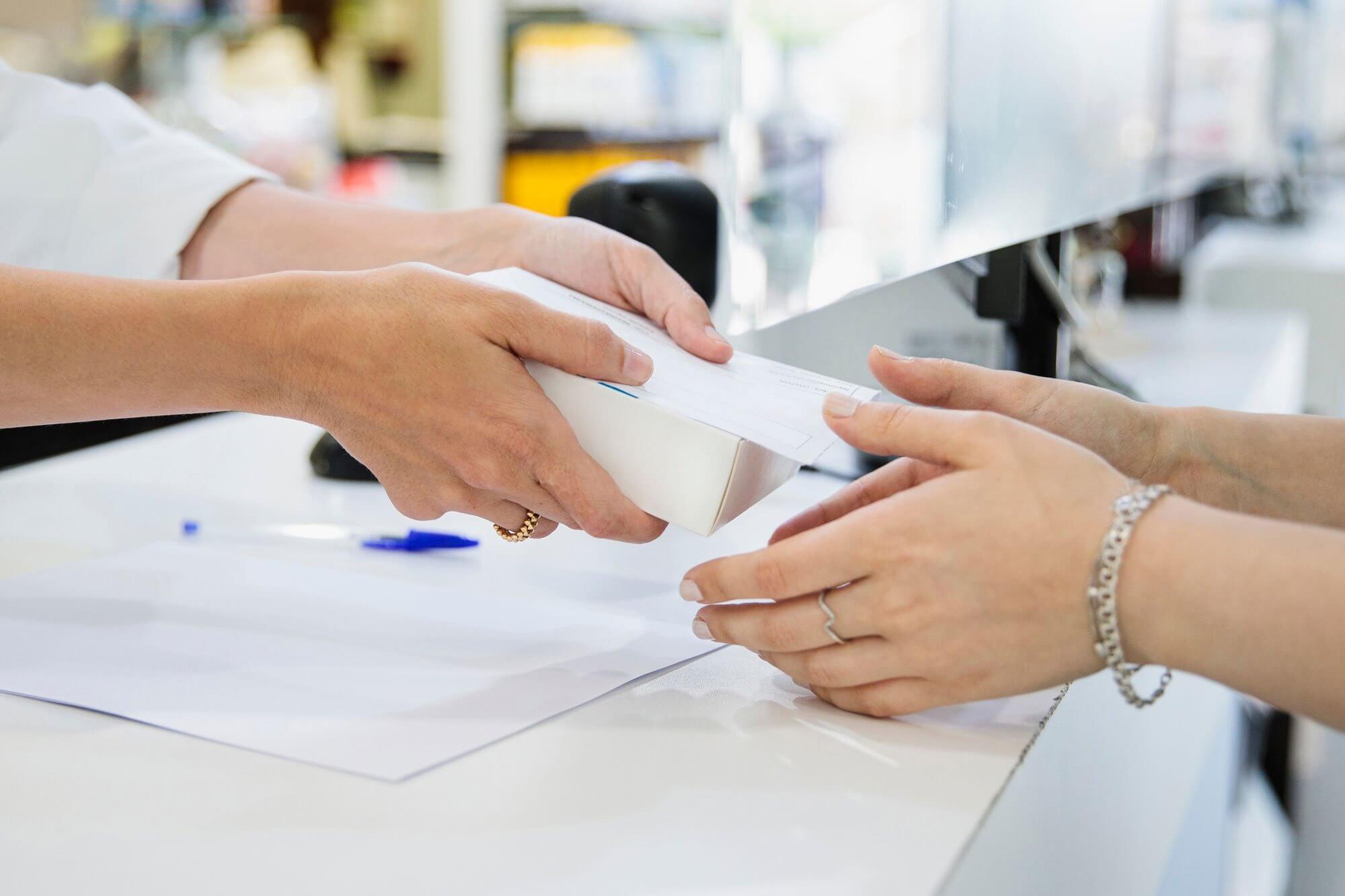 Two people exchanging a white box over a counter.