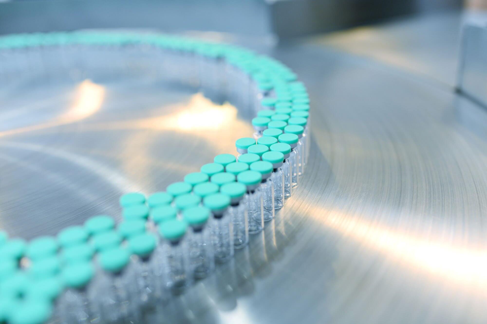 A circular arrangement of small vials with teal caps on a metallic surface.