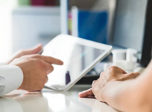 Close-up of hands using a tablet in an office setting.