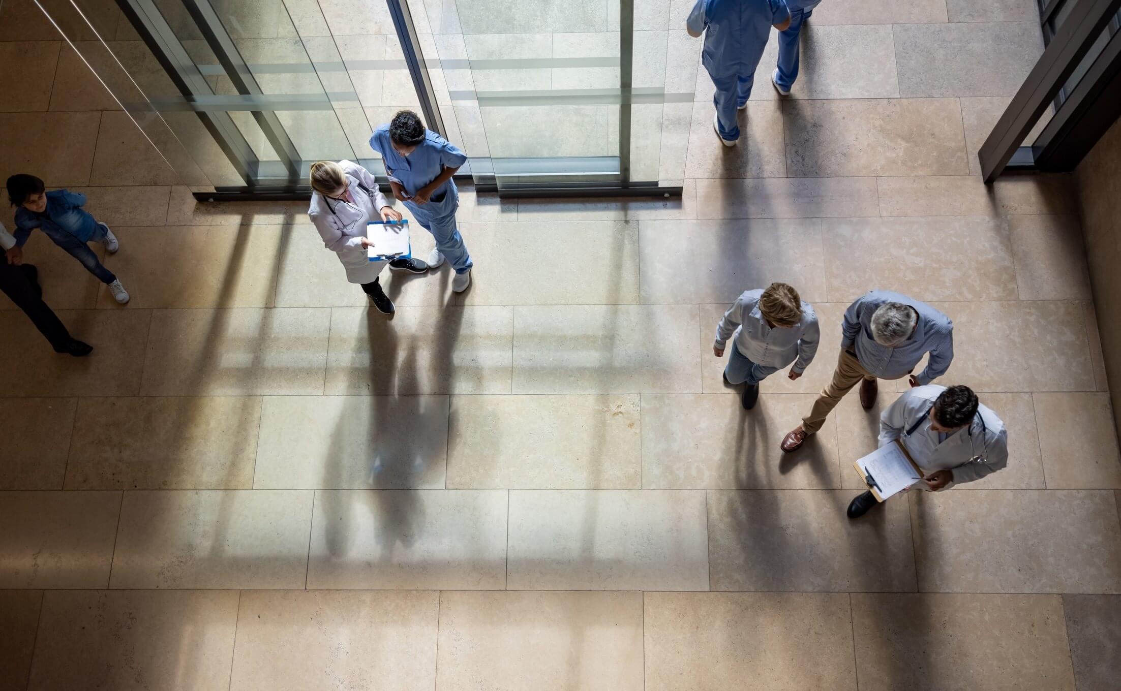 Aerial view of people walking and talking in a hospital corridor.