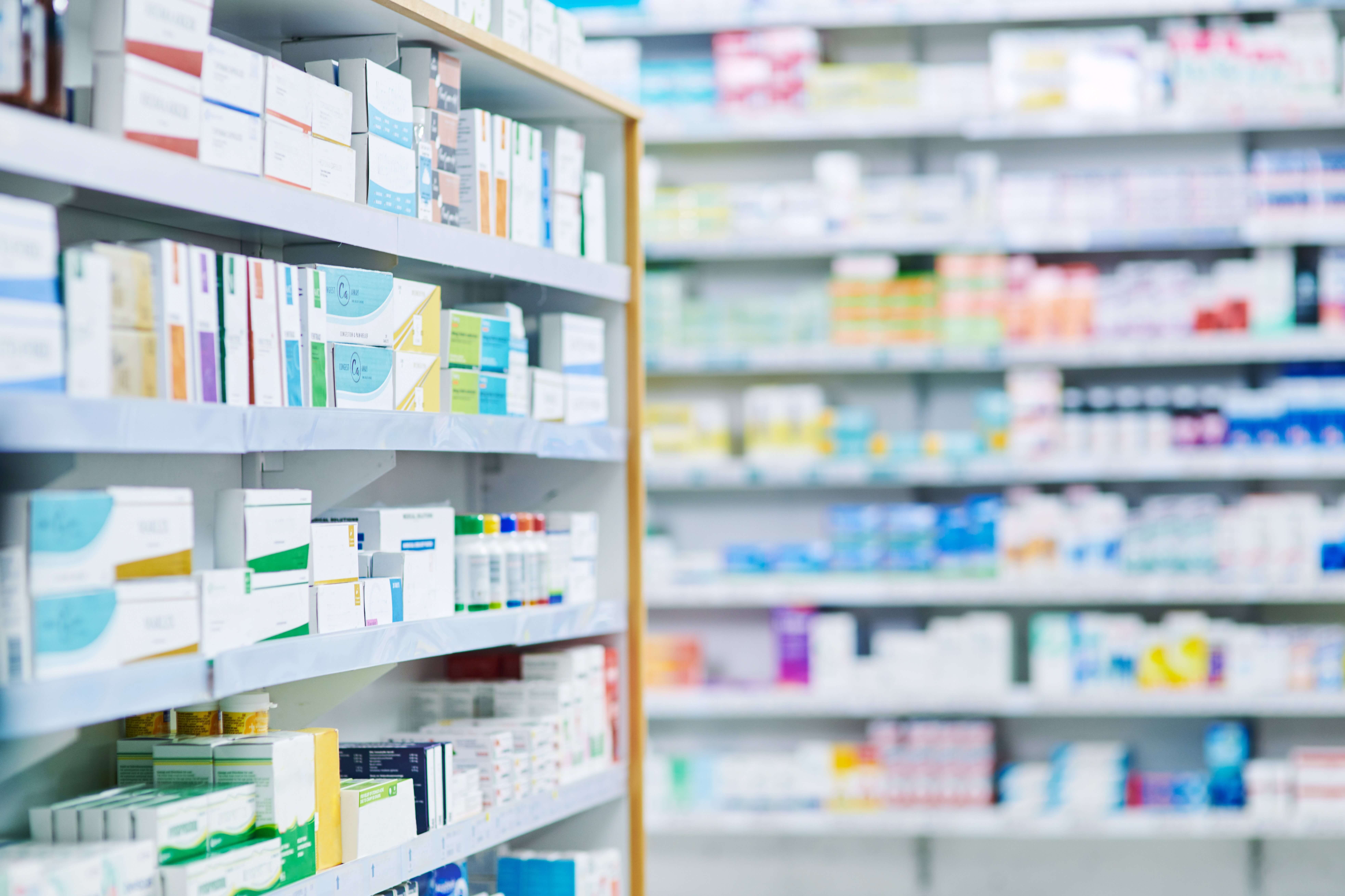 Pharmacy shelves filled with various medications and health products, organized in boxes and bottles.