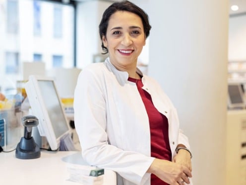 A pharmacist sits in the back of a pharmacy