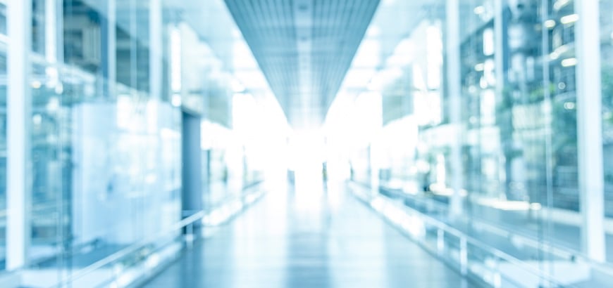 Blurry image of a brightly lit, modern hallway with glass walls.