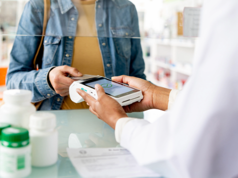 A person in a denim jacket pays with a card reader held by another individual.