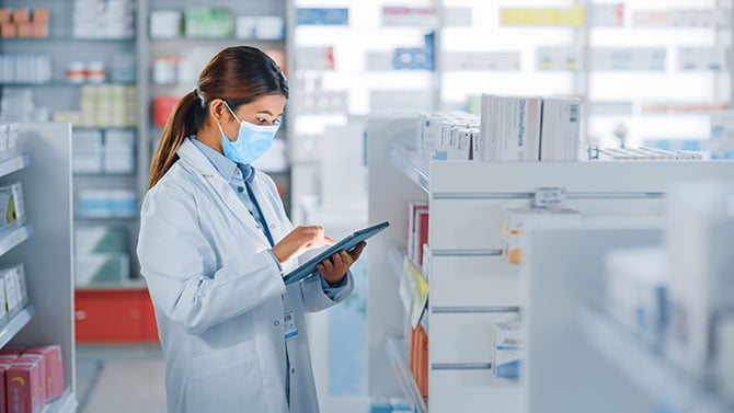 Pharmacist using a tablet inside the pharmacy.