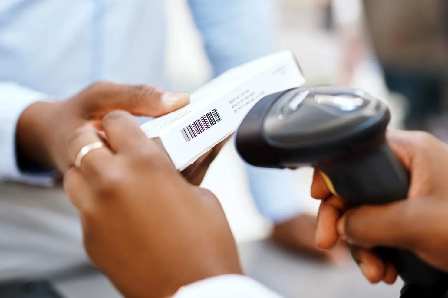 Hands using a handheld scanner to scan a barcode on a box.