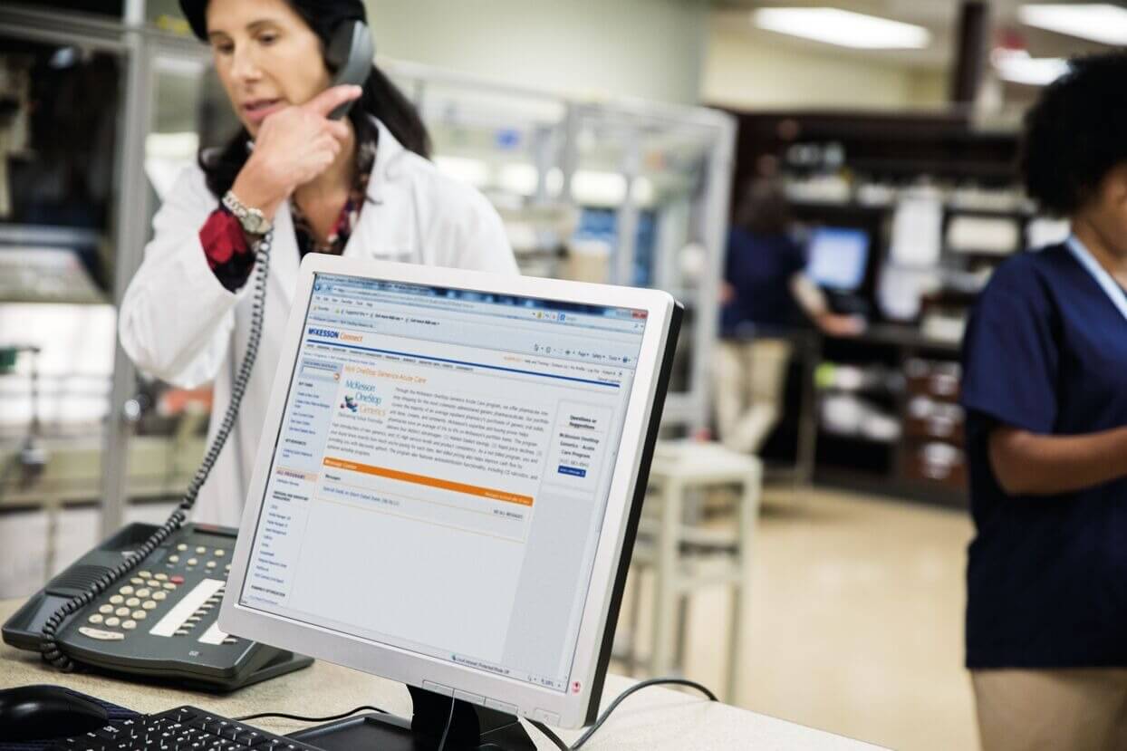 A computer monitor displaying a webpage in an office with people working in the background.