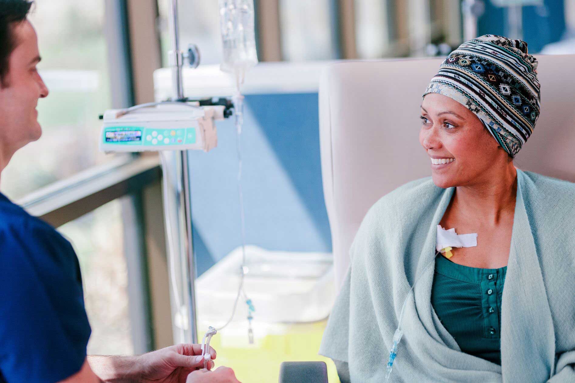 Person receives IV treatment in a medical facility while a healthcare worker provides assistance.
