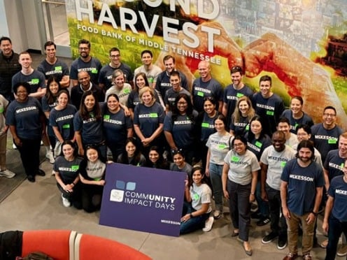 A group of people wearing McKesson shirts pose with a "Community Impact Days" sign at Second Harvest.