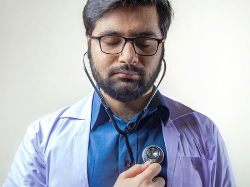 A doctor with a stethoscope listening to his own heartbeat