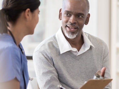 A man sits and chats with his doctor