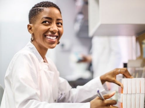 A pharmacist at a desk sorting prescription pill boxes.