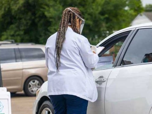 A worker speaking to a customer in their car at a drive through COVID-19 testing site