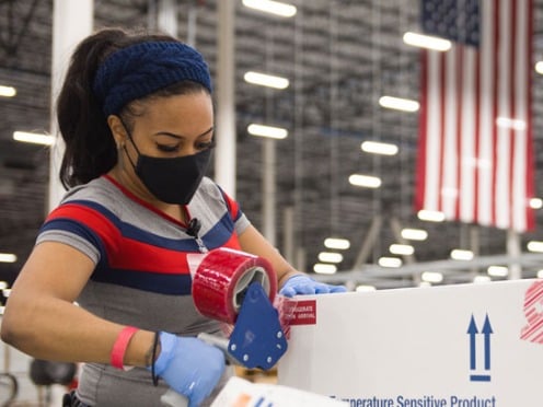 A worker taping boxes shut in a distribution center