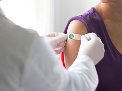 A pharmacist places a bandaid on a patients arm