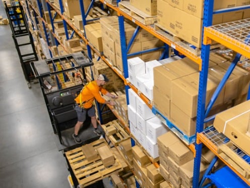 A McKesson warehouse employee restocks the shelves with large boxes