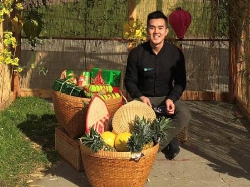 A person sitting behind two large wicker baskets containing fruit and gifts