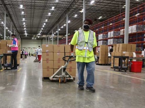 An employee pulling a pallet of boxes in a distribution facility