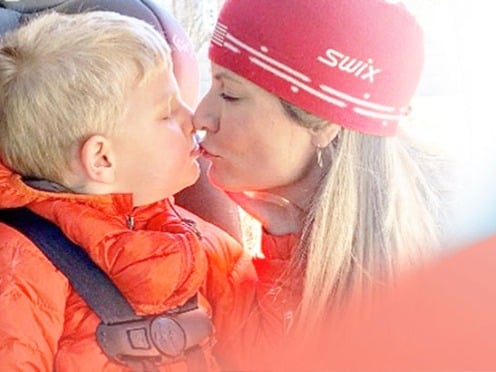 A mom kissing her small son sitting in a car seat