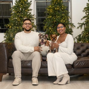 AlRitia Oden sitting on settee with her husband and dogs
