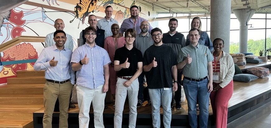 a dozen people standing smiling with showing thumbs up