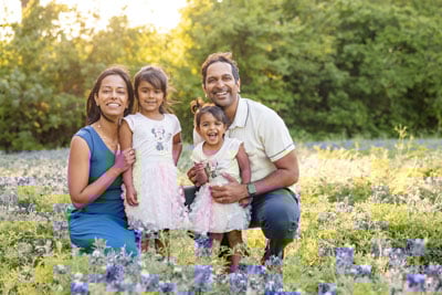 Ram Cheruvu with wife and two small children smiling in field of flowers